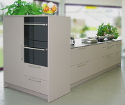 Rotpunkt-Küche: Musterküche mit Kochinsel | Geräteschrank, Fronten Mattlack braun Arbeitsplatte Laminat Farbe Beton